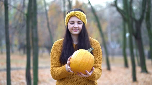 Woman Holding Pumpkins in Hands on an Autumn Sunny Day in the Forest alt