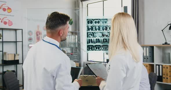 Male and Female Doctors which Learning Patient's X-ray and Discussing Treatment alt