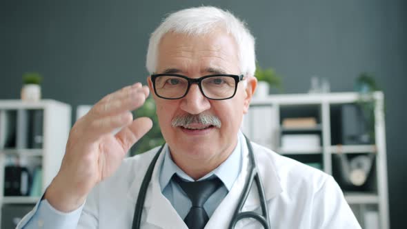 Portrait of Grey-haired Man Doctor in White Uniform Smiling Alone in Office Room alt