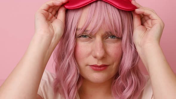 Tired Sleepy Woman Wears Eyemask Wants to Sleep Displeased to Wake Up Very Early Poses on Pink Wall