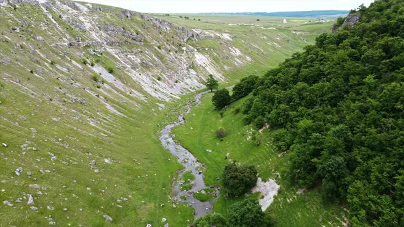 Aerial drone view of nature in Moldova. Valley with floating narrow river, hill slopes and forest alt