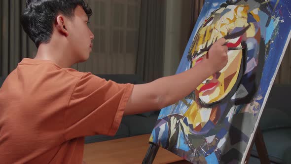 Asian Artist Boy In Wheelchair Painting A Girl's Face On The Canvas alt