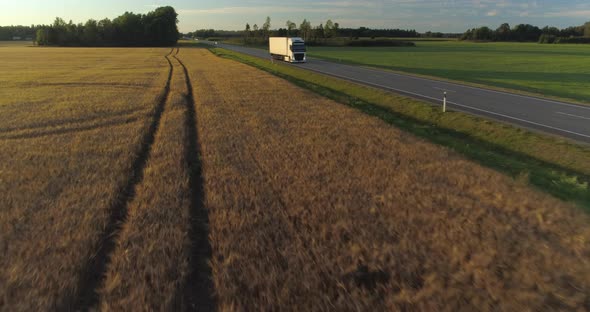 Aerial View of Cargo Truck Delivering Goods on Highway in Countryside at Sunset alt