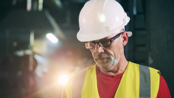 Male Engineer in Safety Wear with Light Flashing Behind Him alt