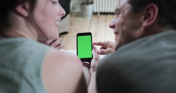 Young adult couple looking at a smartphone together with green screen