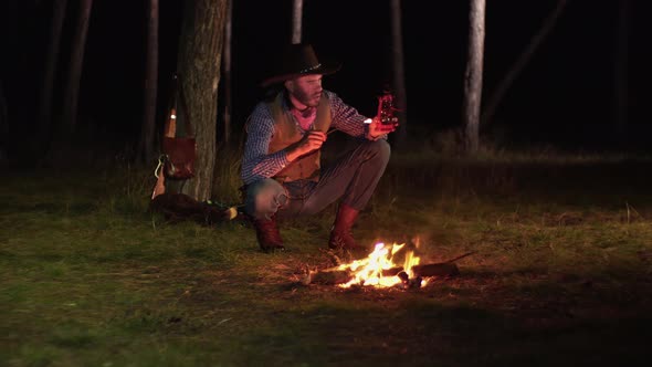 Cowboy Lights a Kerosene Lamp in the Forest at Night alt