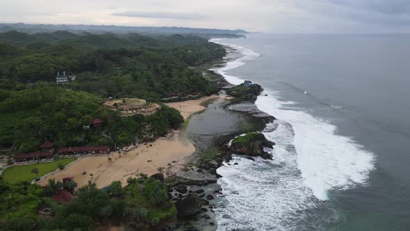 Aerial view of tropical beach in Gunung kidul, Indonesia with green and rocky cliff. alt