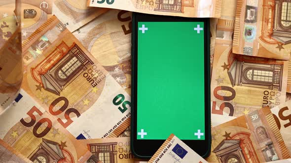 50 euro banknotes currency falling near the mobile phone with green screen chroma key trackpoint.