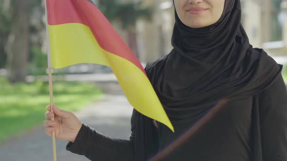 Unrecognizable Happy Muslim Immigrant Posing with German Flag on Sunny Day Outdoors. Smiling Young alt