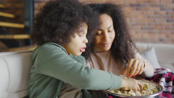 Closeup Happy Son and Mother Watching Tv Covered with Blanket and Eating Popcorn alt