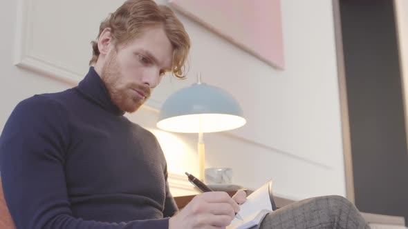 Man Writing in Notebook at Home alt