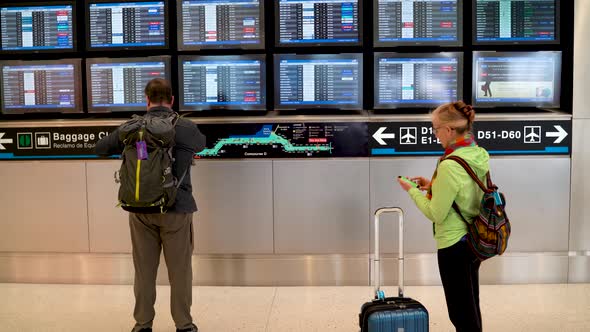 Woman looks for her flight on the flight information display system in an airport. alt