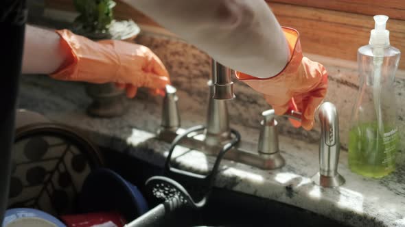 Hands in Orange Gloves Wash Dishes in the Kitchen alt