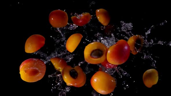 Halved and Whole Apricots Bouncing Towards the Camera alt
