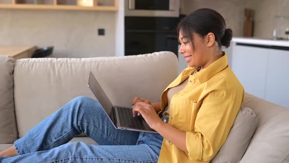 Young Multiracial Beautiful Woman Using Laptop at Home Lying Down on the Couch at Home
