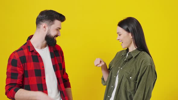 Portrait of Happy Young Couple on Yellow Background Hitting Fist on Fist Gesture Done Successful alt