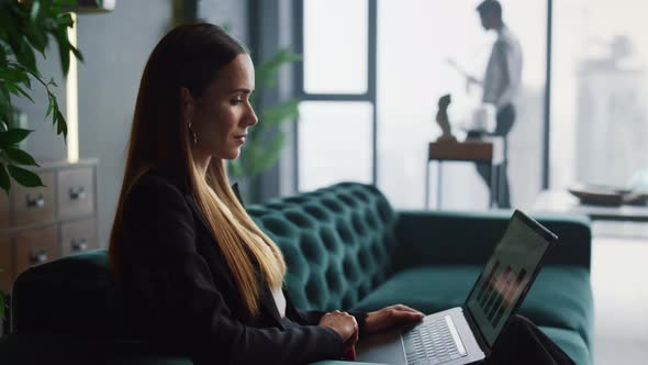 Businesswoman Using Laptop Computer in Office. Businessman Walking Indoors alt