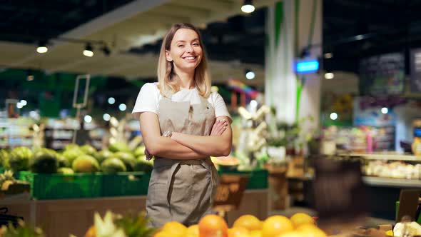 portrait of saleswoman, woman smiling and looking at camera in supermarket.  alt