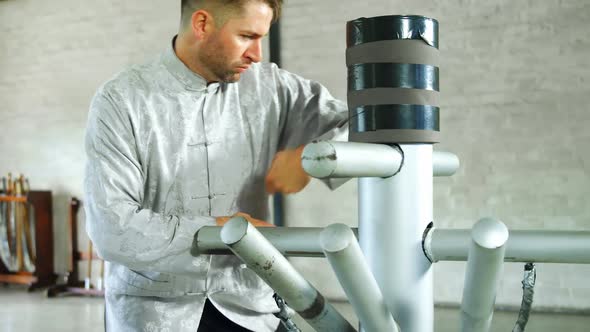 Kung fu fighter practicing martial arts with wooden dummy alt