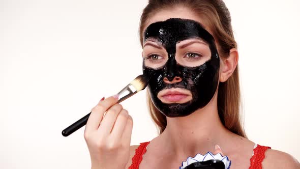 Girl Applying Black Mask to Face alt
