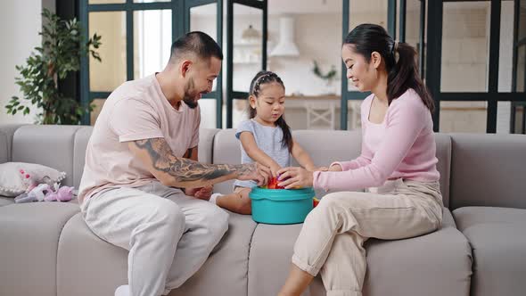 Asian Family Plays Toys Sitting on Grey Couch Together alt