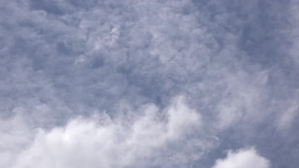 Dreamy white clouds moving across a blue sky.