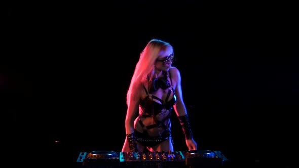 Erotic DJ Blonde Girl in Neon Light Behind the Decks alt