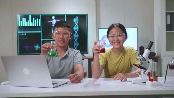 Young Asian Boy And Girl Smiling To Camera While Holding Tubes. Study With Scientific Equipment alt