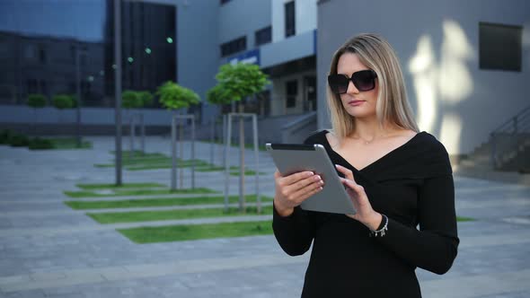 Businesswoman Wearing Sunglasses Using Digital Tablet in Financial District alt
