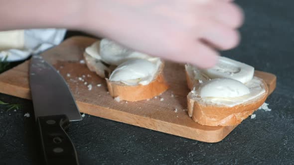 Woman's Hand Salted Sandwiches with Bread, Butter and Eggs on Wooden Board