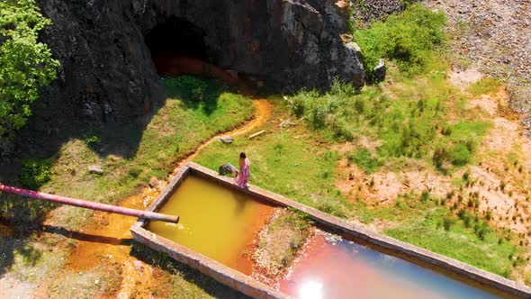 Aerial of a girl in a long dress walking on concrete water reservoir near abandoned mine in Madzharo alt