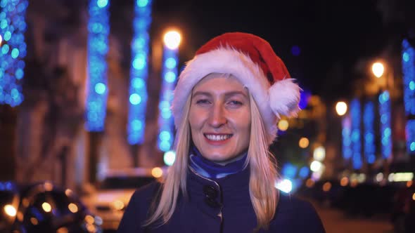 Portrait of a woman smiling at the camera and playing in a Santa hat alt