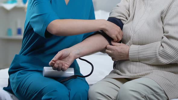 Nurse Measuring Aged Female Patient Blood Pressure in Nursing Home, Medicare alt