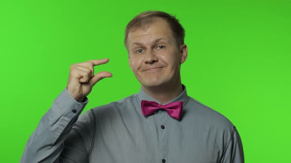 Man Looking at Camera Showing a Little Bit Gesture, Feeling Sceptical About Small Size, Low Scale alt