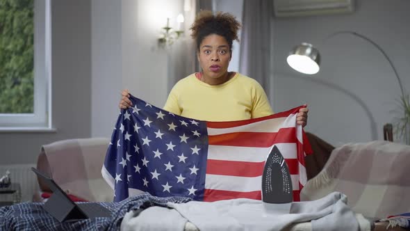 African American Woman with USA Flag Cheering Watching Football Match at Home Making Disappointed alt