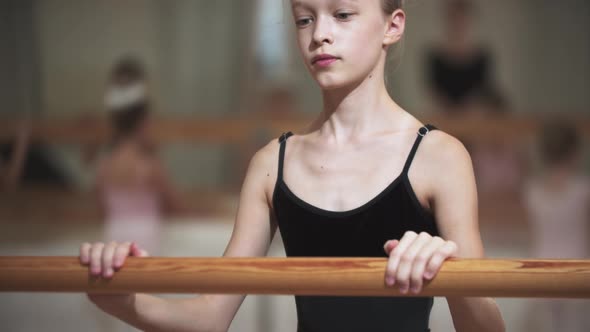 Skinny Little Girl Holding By a Stand in Ballet Studio alt