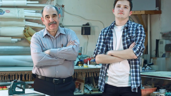 Portrait of two workers standing in workshop and looking