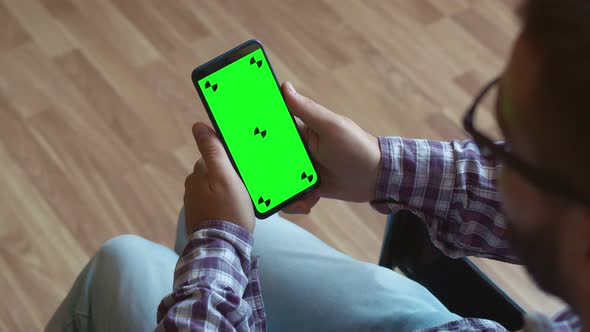 Disabled Person man clicks on the chromakey phone screen, back view. Disabled Person special needs alt