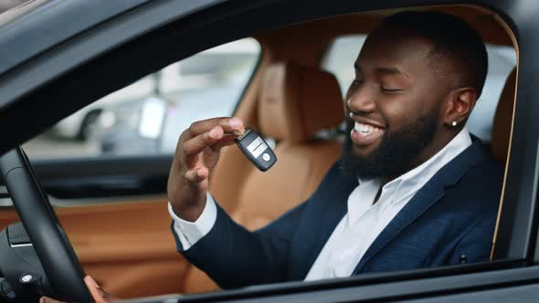 Closeup Businessman Shaking Key in New Car. African Man Smiling in Vehicle alt