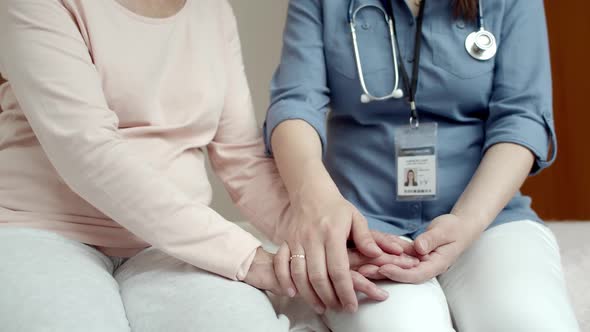 Female Home Caregiver Stroking Hands of Elderly Woman Patient
