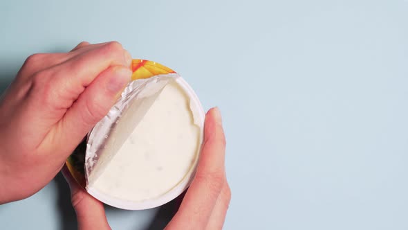 Fresh Organic Yogurt for Proper Nutrition. Female Hands Slowly Open the Lid of Yogurt, Isolated on a
