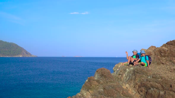 Boys Are Sitting on a Rock on the Shores of the Mediterranean Sea alt