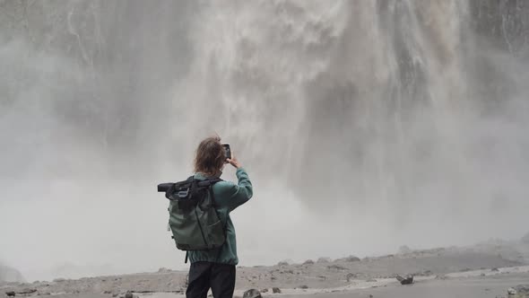 Man traveler with backpack goes and takes pictures of waterfall Karakaya-Su, Jilly Su, Caucasus