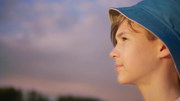 Profile of a Happy Boy in a Hat Looking at the Beautiful Blue Sky