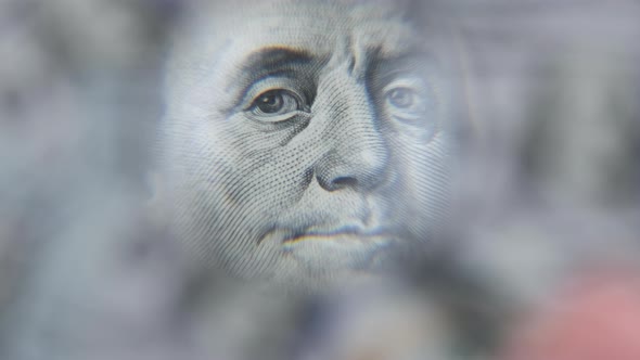 Lot of One Hundred Dollars Bills Inspecting Under Magnifying Glass alt