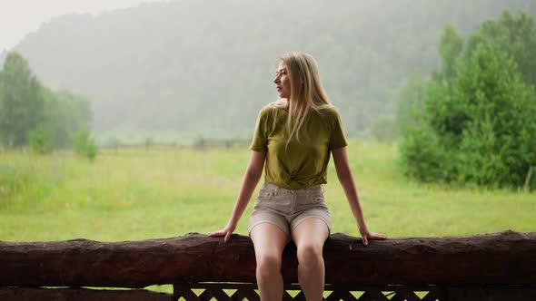 Thoughtful Lady Enjoys Nature Beauty Sitting on Log Fence alt
