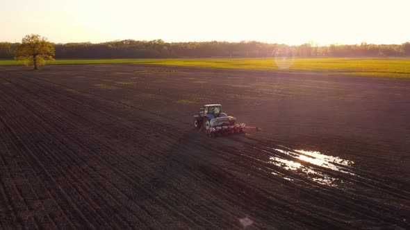 Tractor Working in Field at Sunset alt
