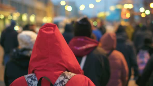 Red Hooded Activist of Political Rally Walks on Street Under Police Flash Lights alt