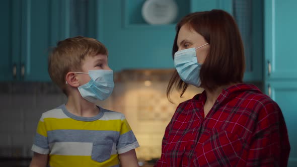 Family in face protective masks giving high five at home alt