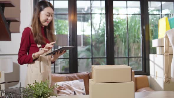 Smiling Asian female small business owner giving packaging boxes to customer alt